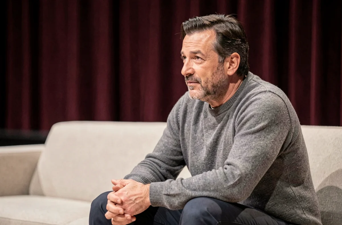 Humoriste en coulisses avant un spectacle, assis pensif, illustrant la discrétion et la vie personnelle protégée d'une star de la comédie française